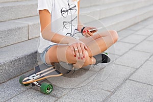 Woman using smartphone while sitting on longboard