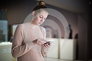 woman using smartphone and standing in art museum