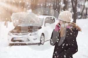 Woman using smartphone to call road assistance. Winter and vehicle concept.