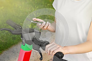 Woman using smartphone to pay and unblock electric kick scooter outdoors, closeup photo