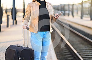 Woman using smartphone in train station while waiting.