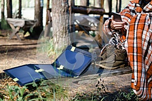 Woman using Smartphone in the woods. Charges using solar panels.
