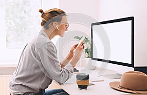 Woman using smartphone while working on computer in home office
