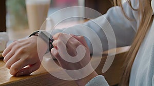 Woman using smartwatch touchscreen wearable technology device. Closeup. Pretty girl making gestures on a smartwatch