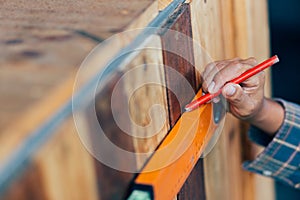 Woman using a spirit level and marking the wall with a pencil