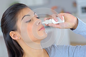 Woman using spray for blocked nose