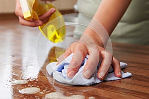 Woman Using Spray Cleaner On Wooden Surface