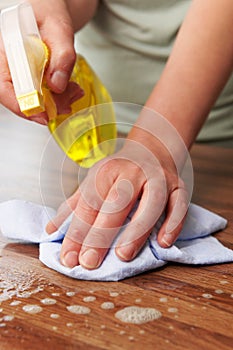 Woman Using Spray To Clean Wooden Surface