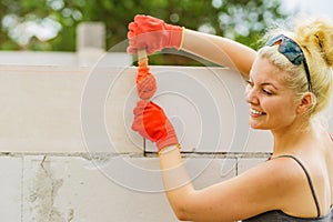 Woman using string as level in wall construction