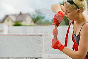 Woman using string as level in wall construction