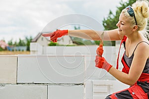 Woman using string as level in wall construction