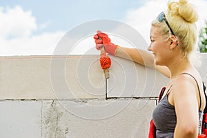 Woman using string as level in wall construction