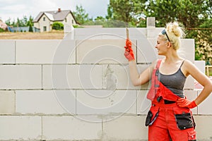 Woman using string as level in wall construction