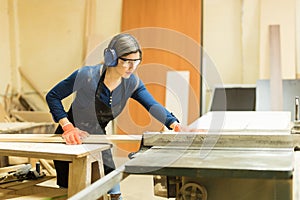 Woman using table saw in a woodshop photo