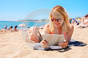 Woman using tablet computer while relaxing on the beach