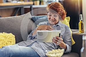 Woman using tablet computer while relaxing on sofa at home