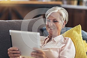 Woman using tablet computer while relaxing on sofa at home