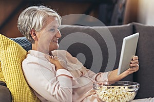 Woman using tablet computer while relaxing on sofa at home