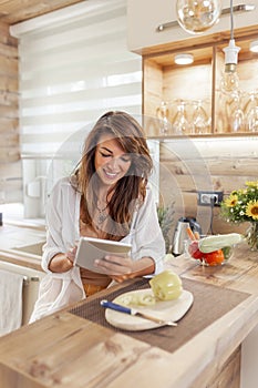 Woman using a tablet computer in search for recipes while cooking