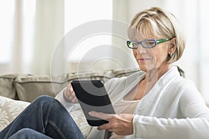 Woman Using Tablet Computer On Sofa