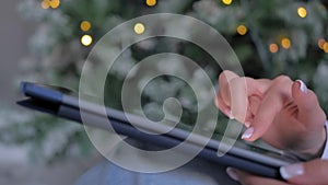 Woman using tablet device, Christmas light background - side close up view