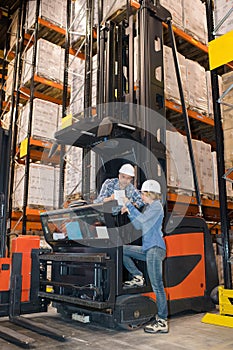 woman using tablet next to man on forklift