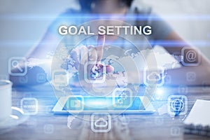 Woman using tablet pc, pressing on virtual screen and selecting goal setting