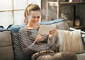 Woman using tablet pc while sitting in apartment