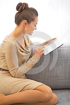 Woman using tablet pc while sitting on divan