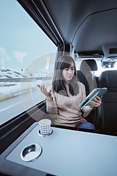 woman using tablet pc while sitting inside a moving car