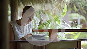 Woman using tablet PC sitting outdoor in tropics