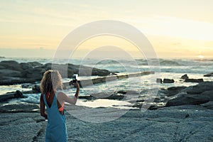 woman using taking photo using smartphone on beautiful beach at sunset sharing travel lifestyle photographing seaside