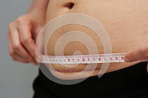 woman using tape measuring the c-section scar of cesarean on belly