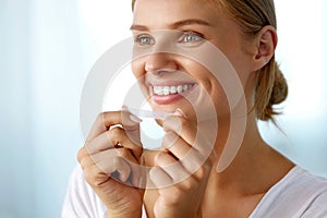 Woman Using Teeth Whitening Strip For Beautiful White Smile photo