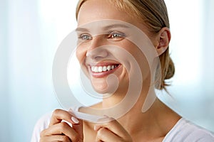 Woman Using Teeth Whitening Strip For Beautiful White Smile photo