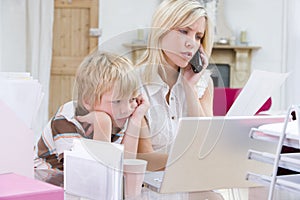 Woman using telephone in office with laptop