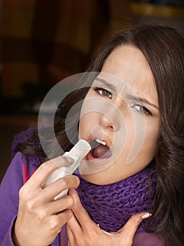 Woman using throat spray.