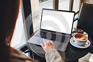 A woman using and touching on laptop computer touchpad with blank white desktop screen in cafe