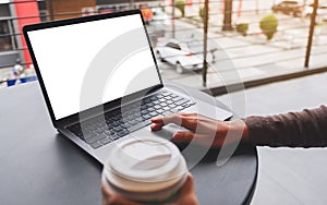 a woman using and touching on laptop computer touchpad with blank white desktop screen while drinking coffee