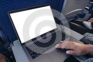 A woman using and touching on laptop computer touchpad with blank white desktop screen while sitting in the cabin