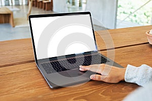 A woman using and touching on laptop computer touchpad with blank white desktop screen on wooden table