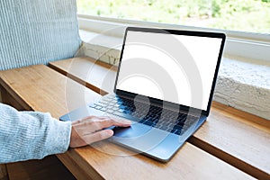 A woman using and touching on laptop computer touchpad with blank white desktop screen on wooden table