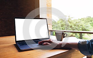 A woman using and touching on laptop computer touchpad with blank white desktop screen on wooden table