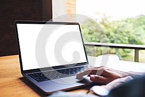 A woman using and touching on laptop computer touchpad with blank white desktop screen on wooden table