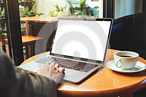 A woman using and touching on laptop touchpad with blank white desktop screen with coffee cup on the table