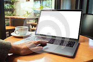 A woman using and touching on laptop touchpad with blank white desktop screen with coffee cup on the table