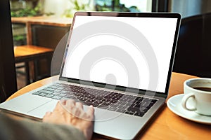 A woman using and touching on laptop touchpad with blank white desktop screen with coffee cup on the table