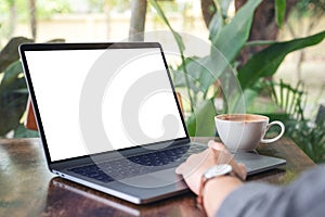 A woman using and touching laptop touchpad with blank white desktop screen with coffee cup on wooden table