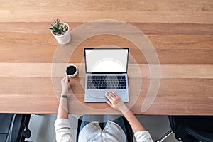 A woman using and touching on laptop touchpad with blank white desktop screen while drinking coffee on