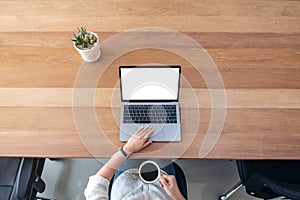 A woman using and touching on laptop touchpad with blank white desktop screen while drinking coffee on